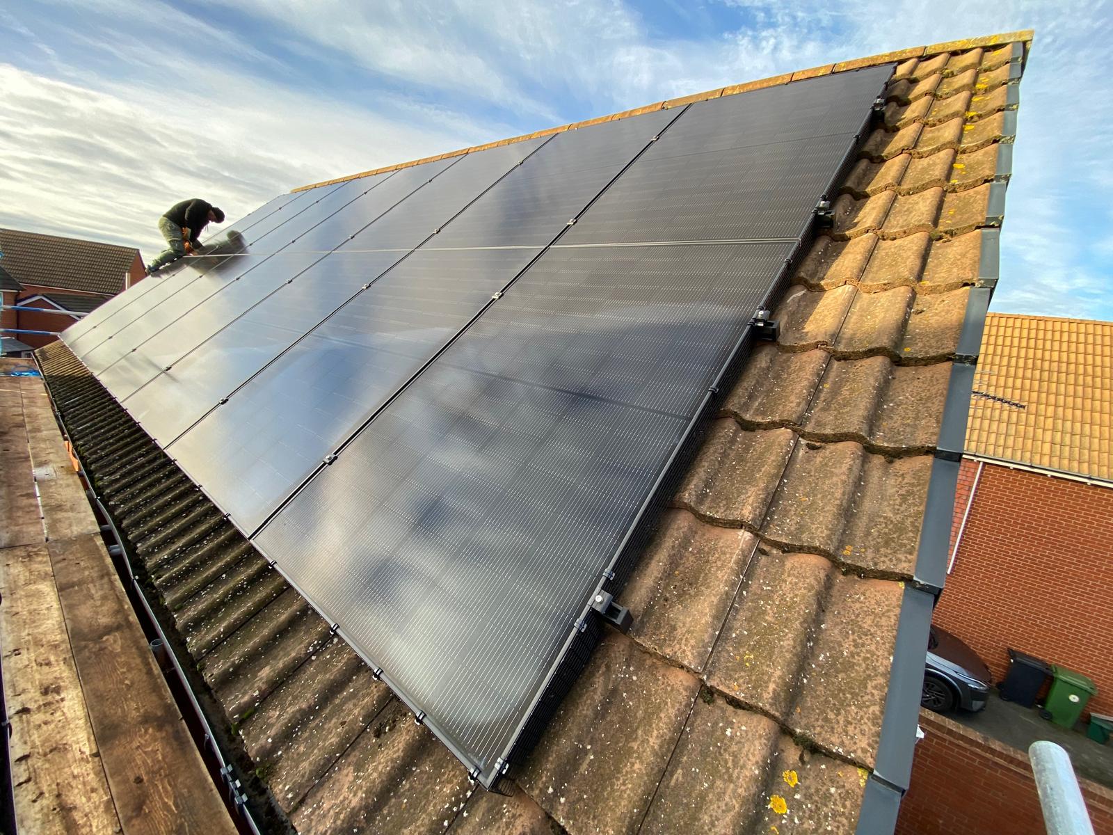 Solar panels being installed on a tiled pitched roof by a Cozy Home Solutions engineer. Photographed by Cozy Home Solutions.
