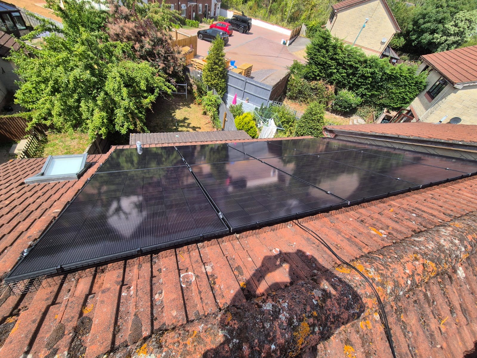Aerial view of all-black solar panels on a red-tiled pitched roof with bird mesh fitted along the eaves at a Newport installation.