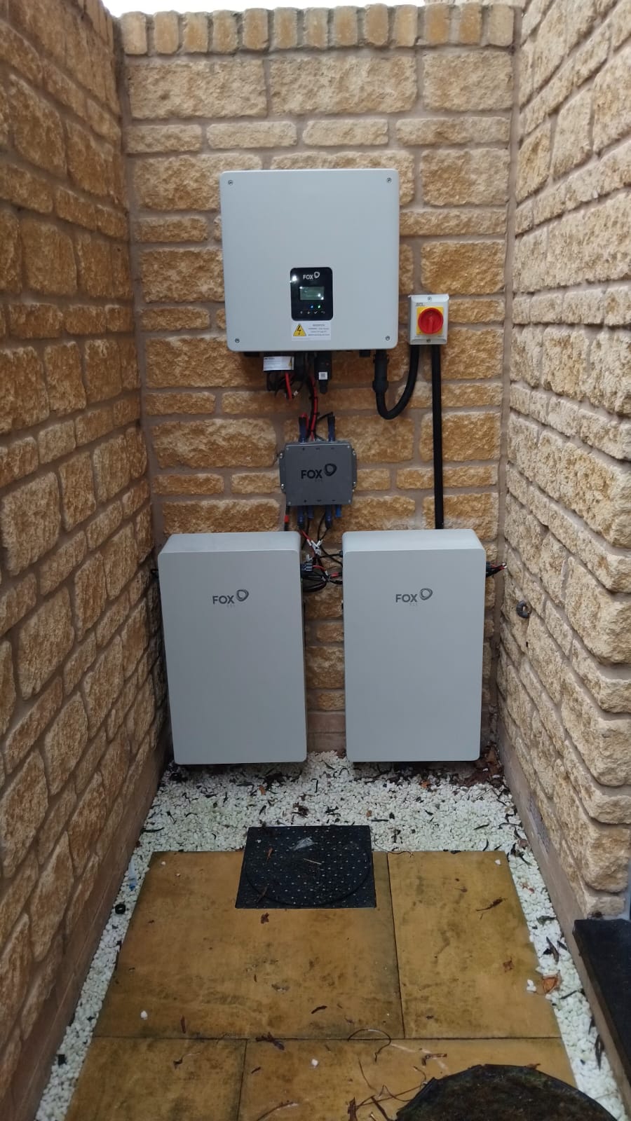 Battery storage and inverter installed in a brick enclosure outside a home. Photographed by Cozy Home Solutions.