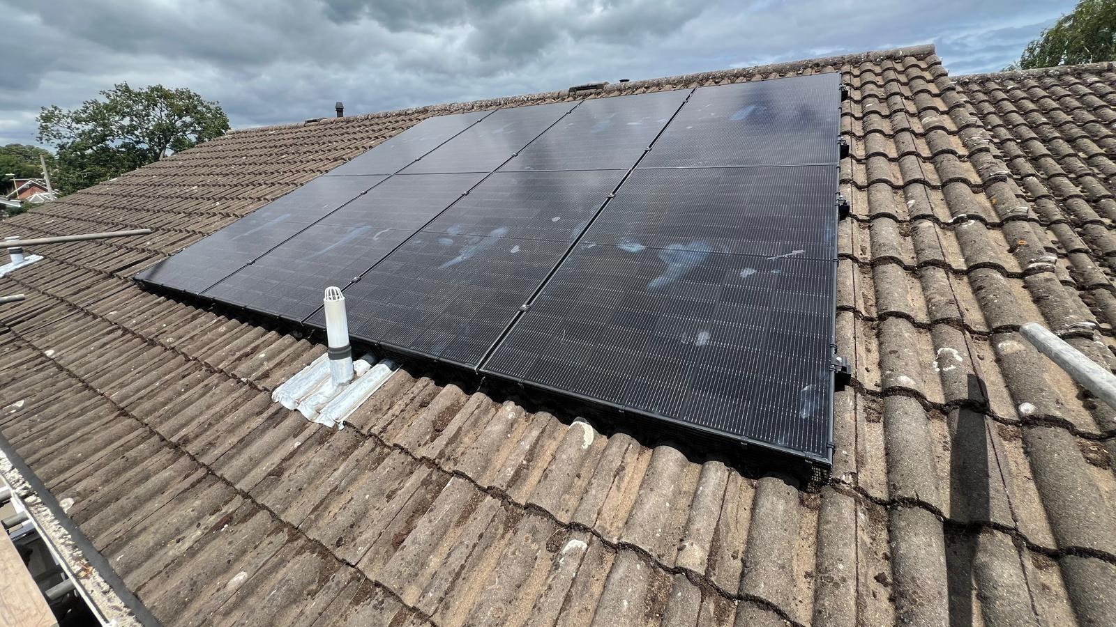 All-black solar panels on a weathered brown tiled roof slope with black bird mesh fitted along the frame edge and a white roof vent pipe beside it, photographed from roof level at a Southampton installation.